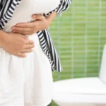 Donna con crampi addominali per via della stitichezza in vacanza
